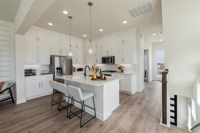 2233 Fort Bliss, Mesquite, TX 75149 - kitchen with stainless steel appliances, a kitchen bar, white cabinetry, light wood finished floors, and recessed lighting