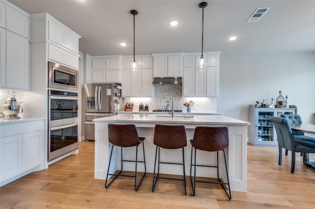 1502 Wild Indigo Dr, Mansfield, TX 76063 - kitchen featuring appliances with stainless steel finishes, under cabinet range hood, tasteful backsplash, light countertops, and recessed lighting