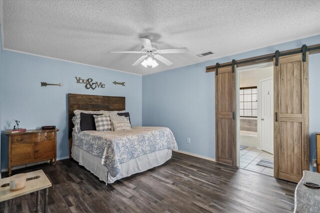 221 Country View Ln, Crandall, TX 75114 - bedroom featuring a barn door, dark wood-type flooring, a textured ceiling, baseboards, and a ceiling fan