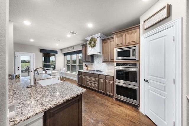 4705 Stillhouse Hollow Ln, Argyle, TX 76226 - kitchen with a sink, stainless steel appliances, dark wood-style flooring, tasteful backsplash, and light stone counters