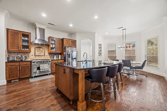 3413 De Vinci Dr, Plano, TX 75074 - kitchen featuring stainless steel appliances, wall chimney exhaust hood, brown cabinets, a breakfast bar, and a sink
