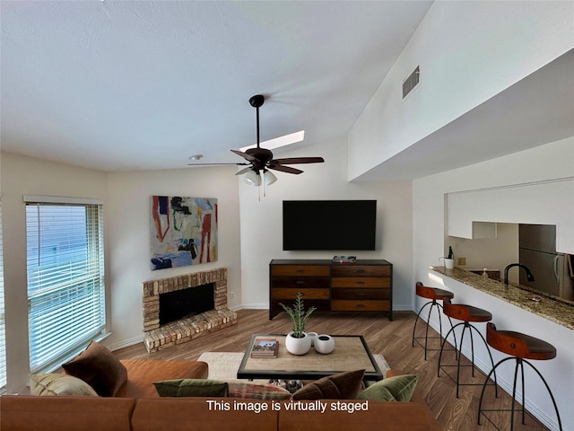 5616 Preston Oaks Rd Unit 508, Dallas, TX 75254 - living area with a ceiling fan, baseboards, a brick fireplace, wood finished floors, and vaulted ceiling