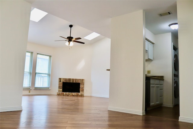 5616 Preston Oaks Rd Unit 508, Dallas, TX 75254 - unfurnished living room with a skylight, stacked washer and clothes dryer, a ceiling fan, wood finished floors, and a fireplace