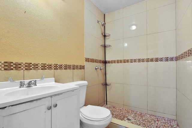 3829 Willing Ave, Fort Worth, TX 76110 - bathroom featuring tile walls, tiled shower, toilet, vanity, and a textured wall