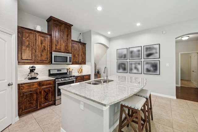 5104 Fringetree Dr, Mckinney, TX 75071 - kitchen featuring appliances with stainless steel finishes, arched walkways, a sink, light tile patterned floors, and recessed lighting