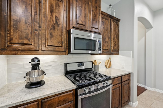 5104 Fringetree Dr, Mckinney, TX 75071 - kitchen featuring stainless steel appliances, light stone countertops, tasteful backsplash, and dark brown cabinets