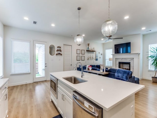6656 Windfall Dr, Fort Worth, TX 76135 - kitchen featuring appliances with stainless steel finishes, a sink, a ceiling fan, a fireplace, and light wood finished floors