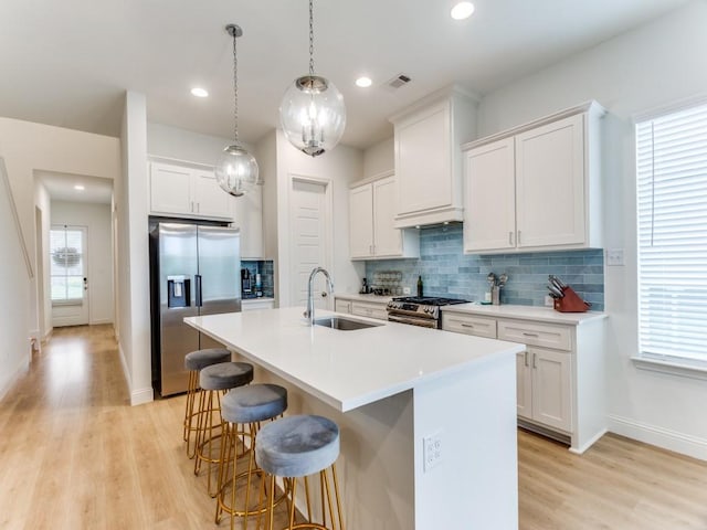 6656 Windfall Dr, Fort Worth, TX 76135 - kitchen featuring a sink, stainless steel appliances, a kitchen bar, light wood-type flooring, and tasteful backsplash