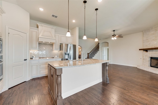 1207 Glasbury Glen Way, Forney, TX 75126 - kitchen with appliances with stainless steel finishes, arched walkways, a sink, dark wood finished floors, and a fireplace