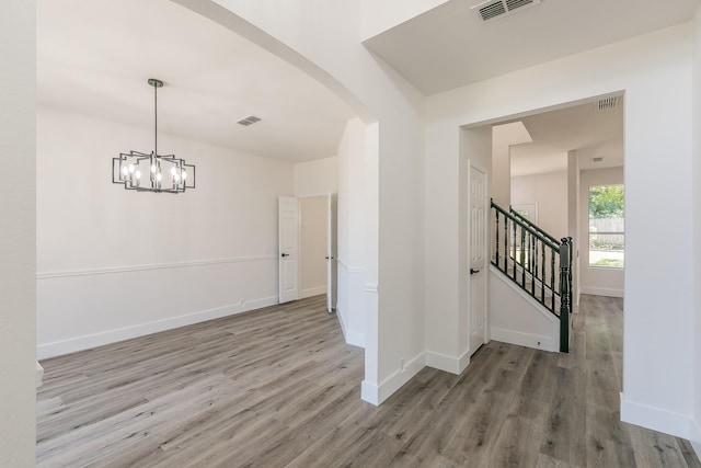 7205 Coventry Cir, North Richland Hills, TX 76182 - unfurnished room with wood finished floors, arched walkways, a chandelier, baseboards, and stairway