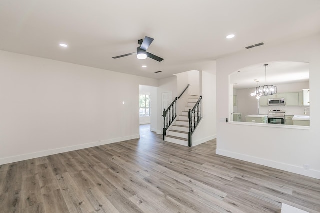 7205 Coventry Cir, North Richland Hills, TX 76182 - unfurnished living room with stairs, arched walkways, light wood-style floors, ceiling fan, and a chandelier