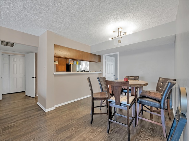 9170 Forest Ln Unit 228, Dallas, TX 75243 - dining room featuring wood finished floors, a textured ceiling, and baseboards