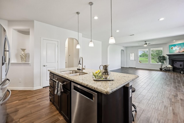 632 Dunster Ln, Saginaw, TX 76131 - kitchen featuring stainless steel appliances, arched walkways, a sink, dark wood finished floors, and baseboards