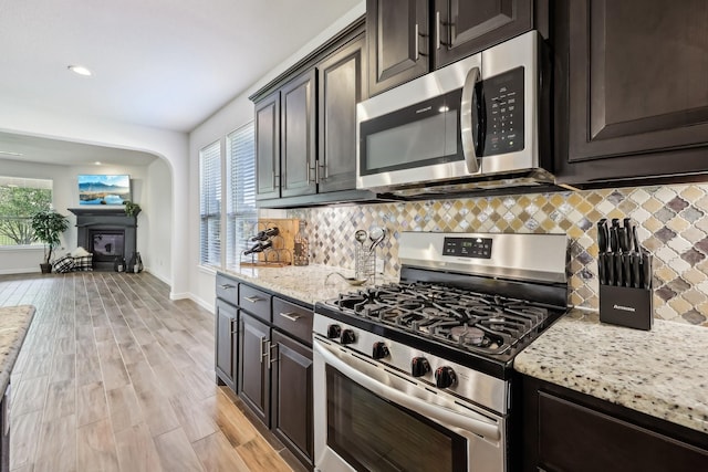 632 Dunster Ln, Saginaw, TX 76131 - kitchen with appliances with stainless steel finishes, tasteful backsplash, light stone counters, light wood-style floors, and baseboards