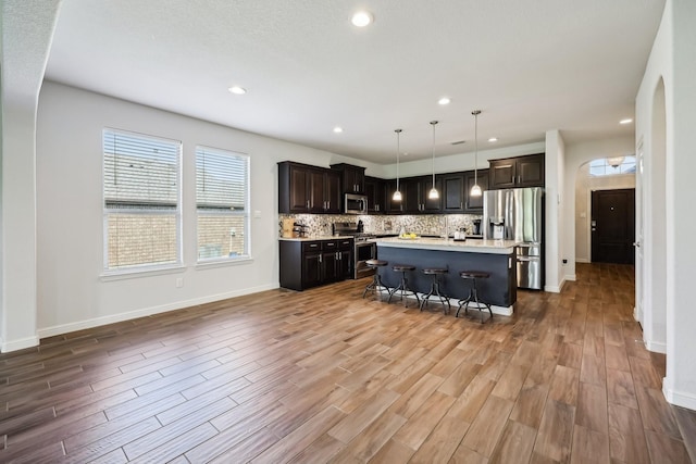632 Dunster Ln, Saginaw, TX 76131 - kitchen featuring appliances with stainless steel finishes, light countertops, decorative backsplash, wood finished floors, and a breakfast bar area
