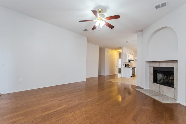 738 Opal Ln, Mesquite, TX 75149 - unfurnished living room featuring ceiling fan, light wood-type flooring, and a tiled fireplace