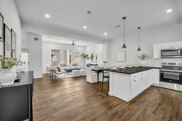 5806 Bryan Pkwy Unit 4, Dallas, TX 75206 - kitchen with appliances with stainless steel finishes, dark countertops, dark wood finished floors, white cabinets, and recessed lighting