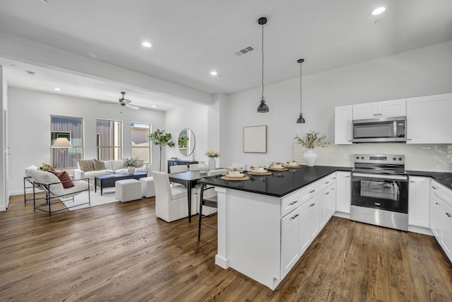 5806 Bryan Pkwy Unit 4, Dallas, TX 75206 - kitchen featuring appliances with stainless steel finishes, a peninsula, dark countertops, open floor plan, and white cabinetry