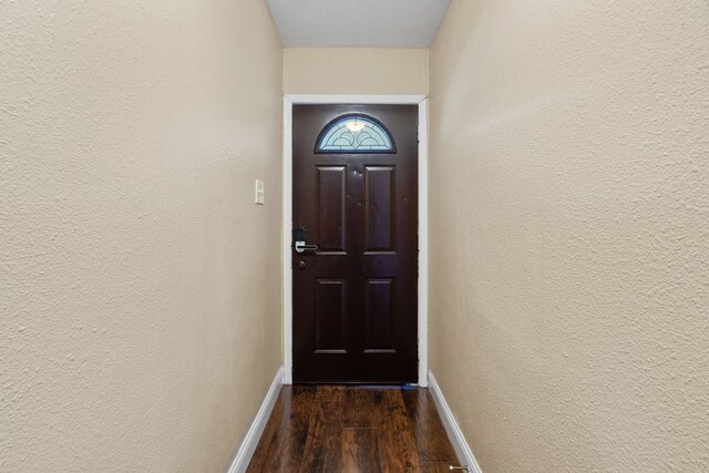 1413 Rockbrook St, Lancaster, TX 75134 - doorway featuring baseboards, dark wood-type flooring, and a textured wall
