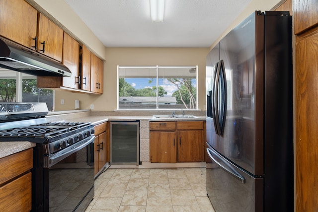 1413 Rockbrook St, Lancaster, TX 75134 - kitchen with refrigerator with ice dispenser, black range with gas stovetop, beverage cooler, under cabinet range hood, and a sink