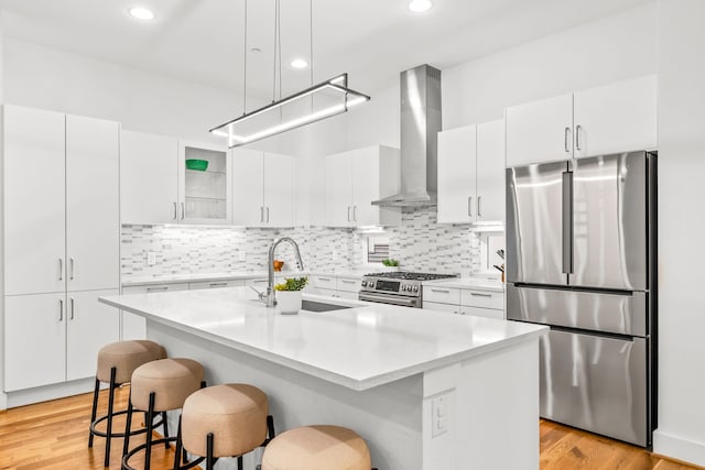 1928 Kearney Ct, Dallas, TX 75204 - kitchen featuring appliances with stainless steel finishes, wall chimney range hood, a sink, a breakfast bar area, and light countertops