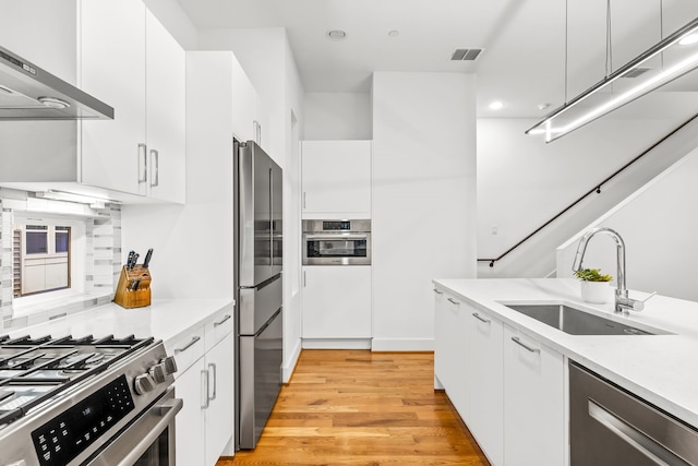 1928 Kearney Ct, Dallas, TX 75204 - kitchen with wall chimney exhaust hood, stainless steel appliances, a sink, light wood-style flooring, and modern cabinets