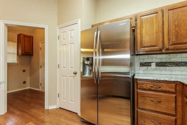 665 Cardinal Ridge Rd, Burleson, TX 76028 - kitchen with stainless steel refrigerator with ice dispenser, decorative backsplash, wood finished floors, brown cabinetry, and light stone countertops