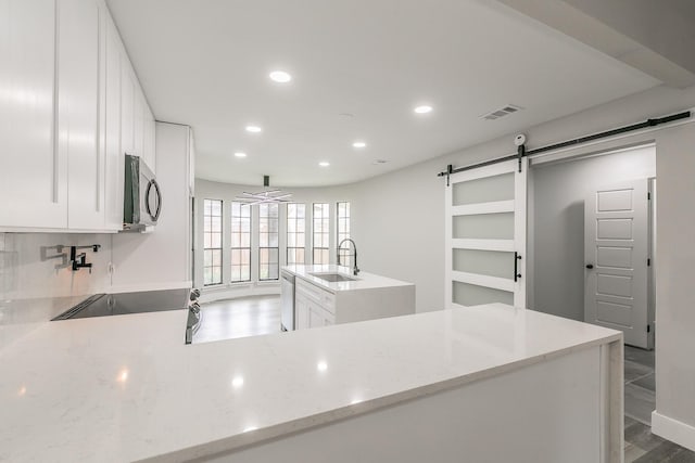 1103 Teakwood Dr, Duncanville, TX 75137 - kitchen with stainless steel appliances, a sink, a barn door, recessed lighting, and white cabinetry