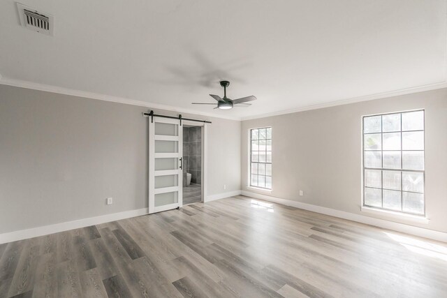 1103 Teakwood Dr, Duncanville, TX 75137 - unfurnished room with ornamental molding, a barn door, a ceiling fan, baseboards, and wood finished floors