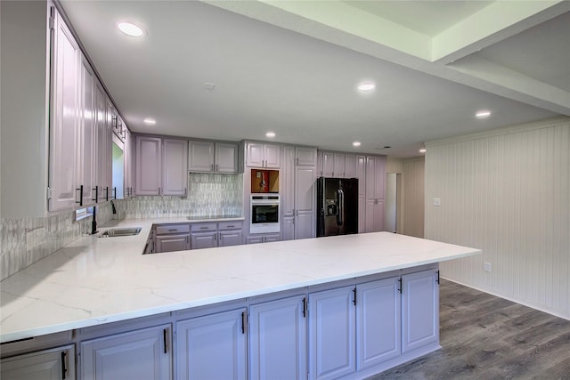 552 Oak Leaf Trl, East Tawakoni, TX 75472 - kitchen featuring black appliances, a sink, a peninsula, backsplash, and dark wood-style floors