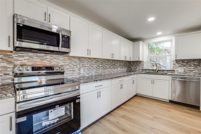 202 Kenway St, Rockwall, TX 75087 - kitchen featuring appliances with stainless steel finishes, a sink, white cabinetry, dark stone countertops, and tasteful backsplash