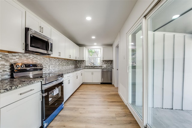 202 Kenway St, Rockwall, TX 75087 - kitchen featuring appliances with stainless steel finishes, dark stone countertops, tasteful backsplash, light wood-style flooring, and a sink