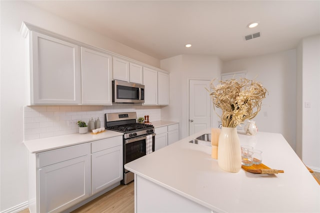 1236 Sequoia Ln, Princeton, TX 75407 - kitchen with stainless steel appliances, light countertops, light wood-type flooring, white cabinetry, and backsplash