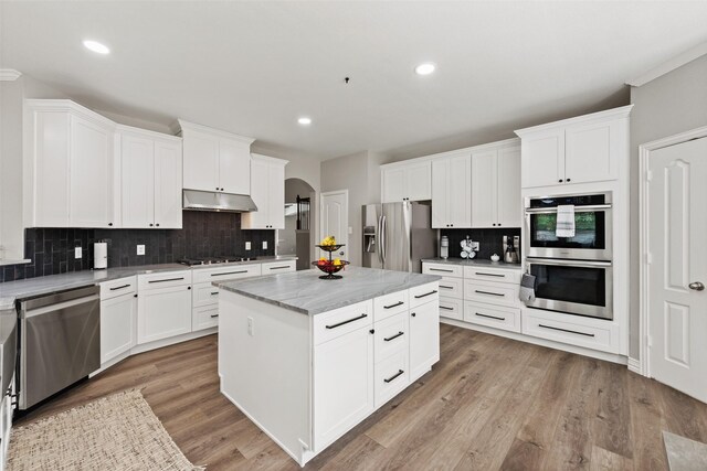 3516 Horace Ave, Fort Worth, TX 76244 - kitchen with appliances with stainless steel finishes, under cabinet range hood, arched walkways, tasteful backsplash, and a center island