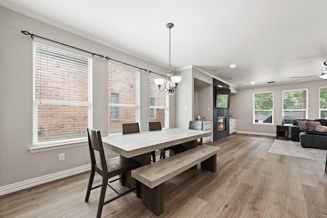 3516 Horace Ave, Fort Worth, TX 76244 - dining area featuring baseboards, crown molding, light wood-style floors, a chandelier, and a glass covered fireplace