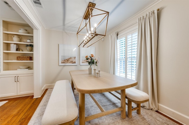 7107 La Vista Dr, Dallas, TX 75214 - dining area featuring ornamental molding, baseboards, light wood-style floors, a chandelier, and built in shelves