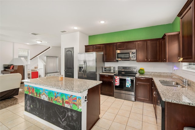 2841 Pacifico Way, Fort Worth, TX 76111 - kitchen featuring appliances with stainless steel finishes, a sink, light tile patterned floors, open floor plan, and a center island