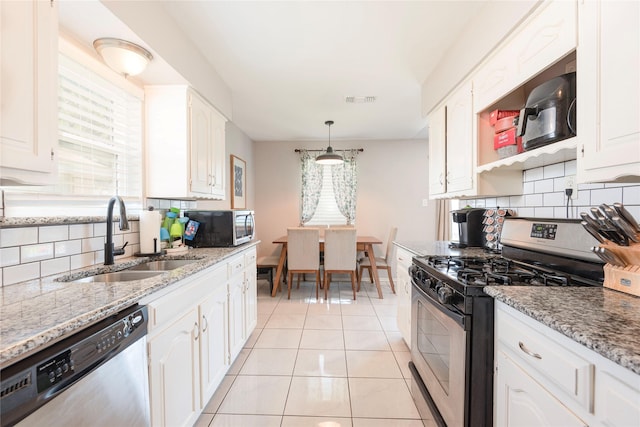 1654 Clarendon Dr, Lewisville, TX 75067 - kitchen featuring appliances with stainless steel finishes, a sink, decorative backsplash, white cabinetry, and light tile patterned floors