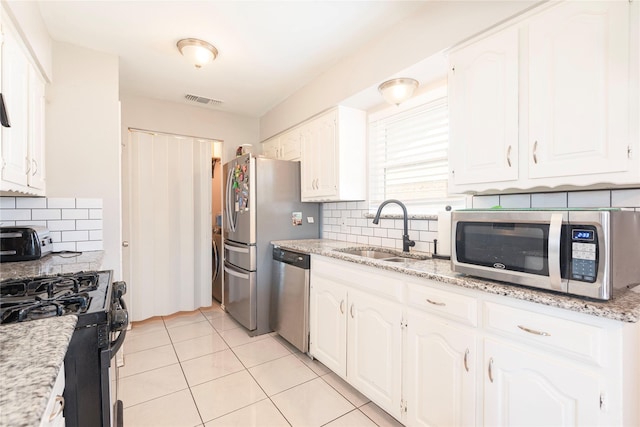 1654 Clarendon Dr, Lewisville, TX 75067 - kitchen featuring appliances with stainless steel finishes, a sink, decorative backsplash, and white cabinetry