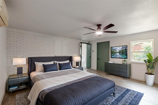 409 Fleming Dr, Hurst, TX 76053 - bedroom featuring a wall mounted air conditioner, a ceiling fan, brick wall, baseboards, and light wood-style flooring