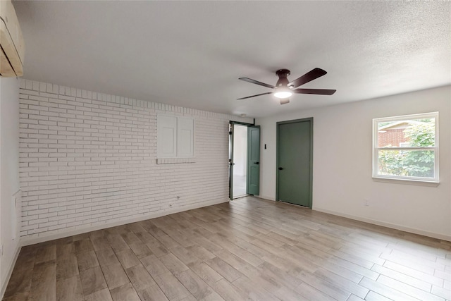 409 Fleming Dr, Hurst, TX 76053 - unfurnished room with brick wall, a ceiling fan, light wood-style floors, baseboards, and a wall mounted air conditioner