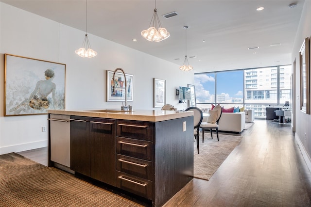 2200 Victory Ave Unit 701, Dallas, TX 75219 - kitchen featuring a chandelier, dark brown cabinetry, open floor plan, a kitchen island with sink, and wood finished floors