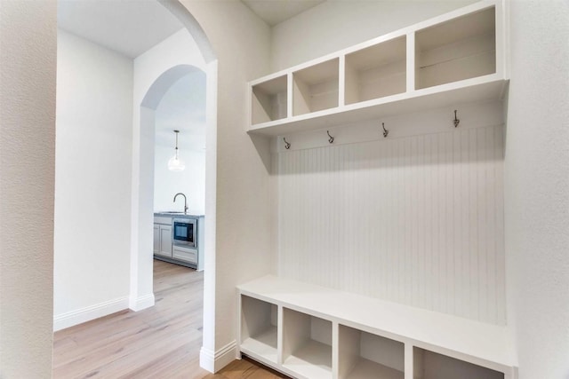 533 Hillcrest Cir, Justin, TX 76247 - mudroom with arched walkways, a sink, light wood-style flooring, and baseboards