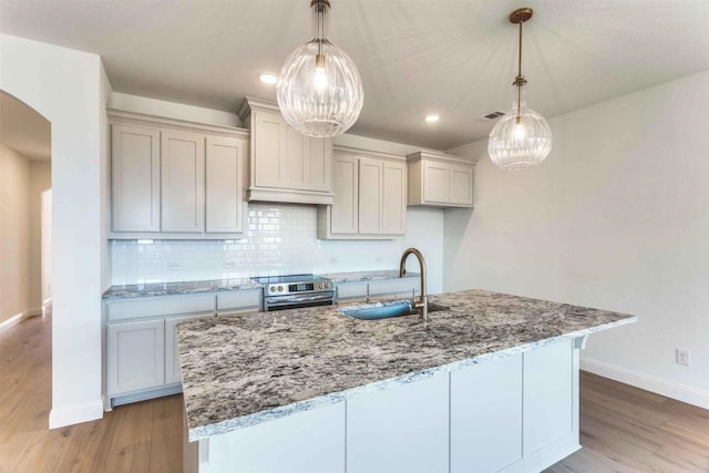 533 Hillcrest Cir, Justin, TX 76247 - kitchen featuring a sink, stainless steel range with electric stovetop, baseboards, light wood-type flooring, and arched walkways