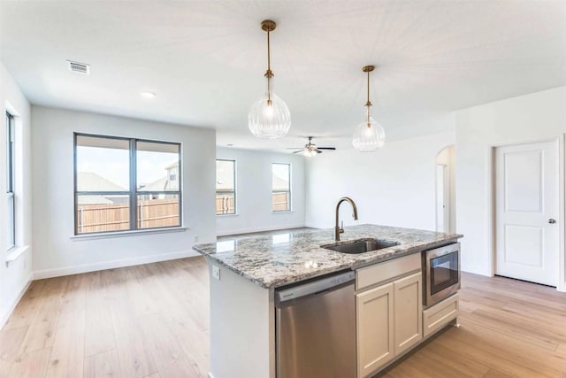 533 Hillcrest Cir, Justin, TX 76247 - kitchen featuring appliances with stainless steel finishes, a sink, light wood-style flooring, hanging light fixtures, and light stone counters