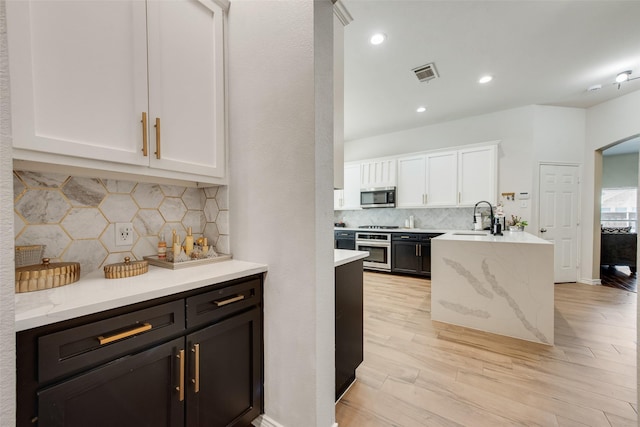 13293 Grayhawk Blvd, Frisco, TX 75033 - kitchen featuring stainless steel microwave, stove, a sink, white cabinets, and light wood-style flooring