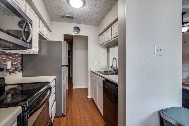1301 Memory Ln Unit 4920, Arlington, TX 76011 - kitchen with black appliances, a sink, light countertops, light wood-style floors, and white cabinetry