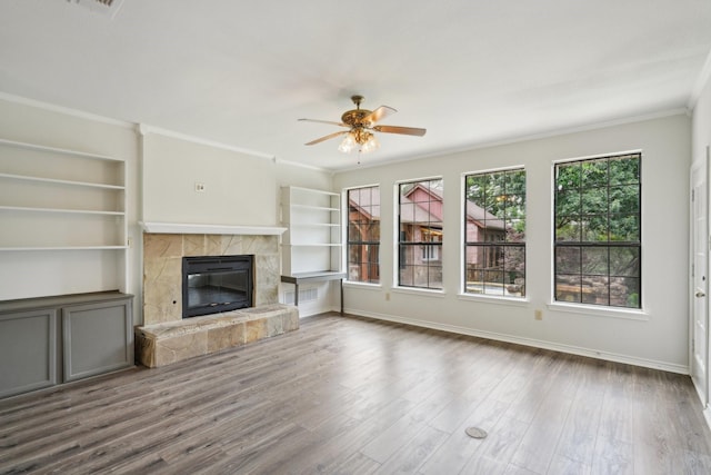 2224 Bluff Ct, Cedar Hill, TX 75104 - unfurnished living room with ceiling fan, crown molding, a tile fireplace, wood finished floors, and baseboards