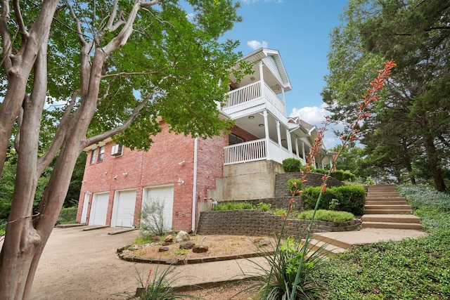 2224 Bluff Ct, Cedar Hill, TX 75104 - view of side of home featuring brick siding, a balcony, an attached garage, driveway, and stairs
