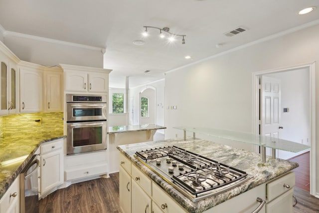 2224 Bluff Ct, Cedar Hill, TX 75104 - kitchen featuring stainless steel appliances, dark wood finished floors, ornamental molding, decorative backsplash, and light stone counters